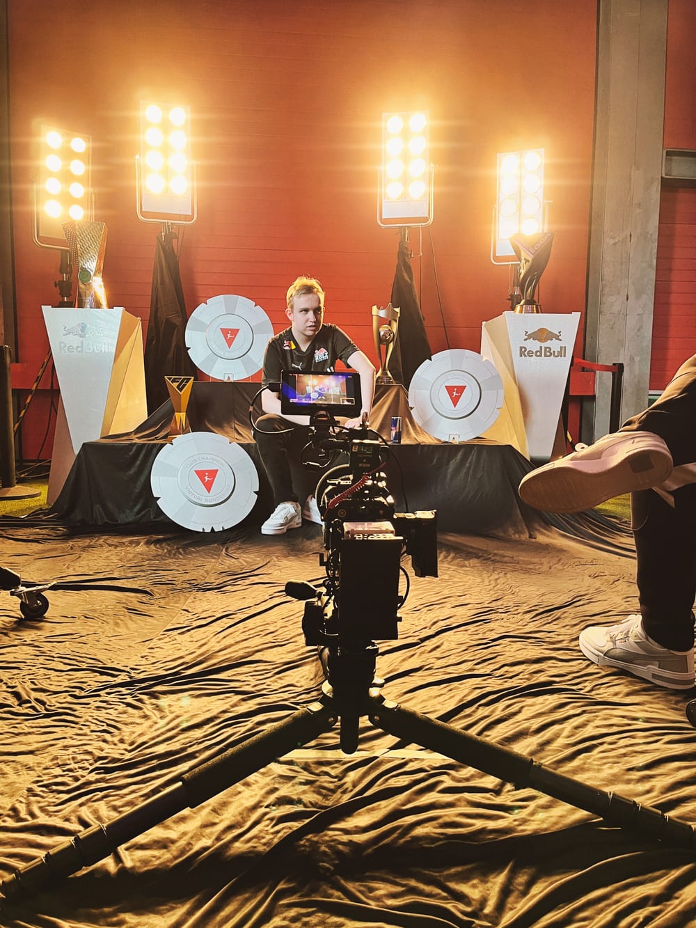 Behind the Scenes: Kamera auf Stativ vor einem Studio-Set mit warmen Scheinwerfern