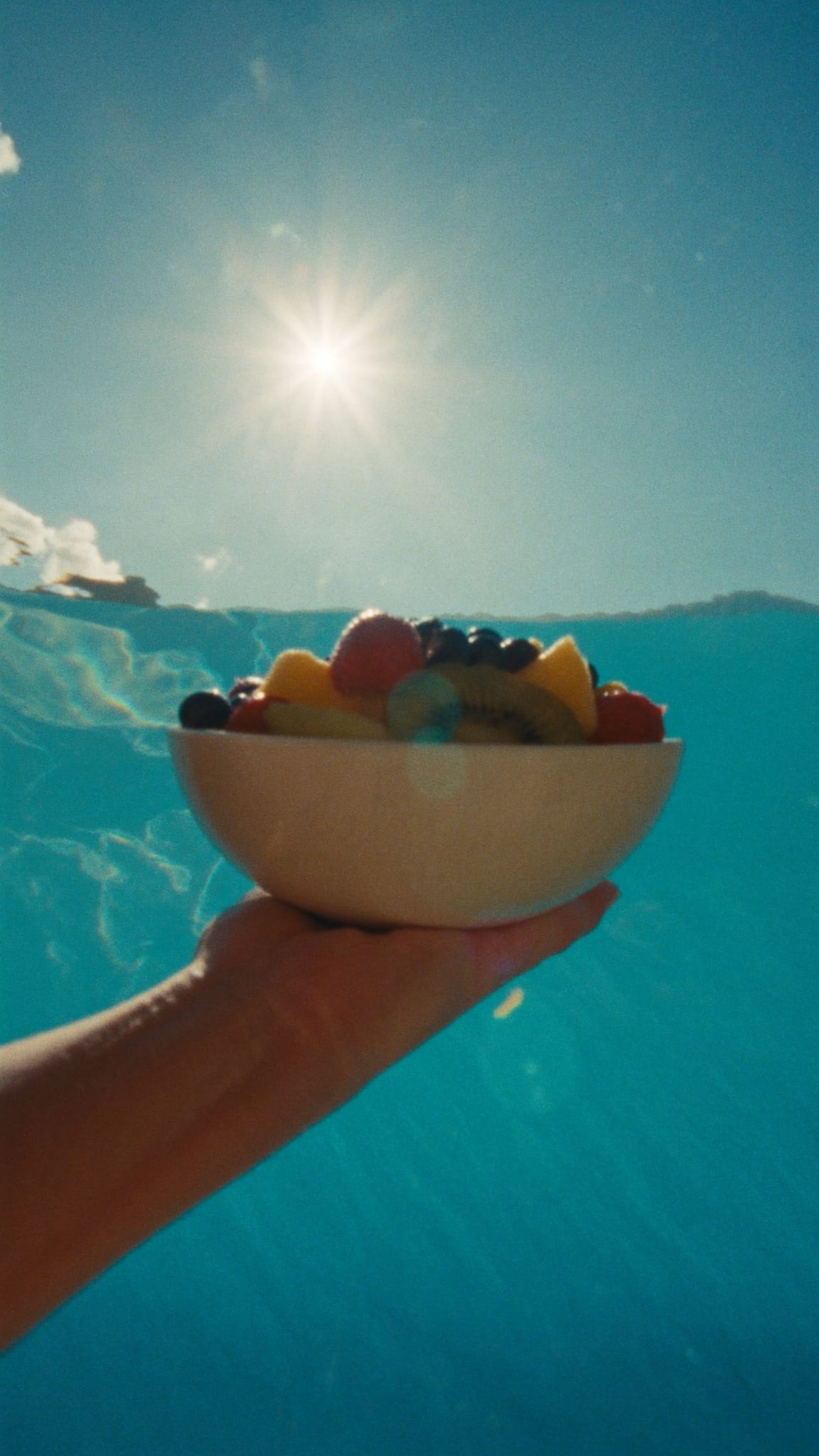 Hand hält eine Bowl vor dem Meer in der Sonne