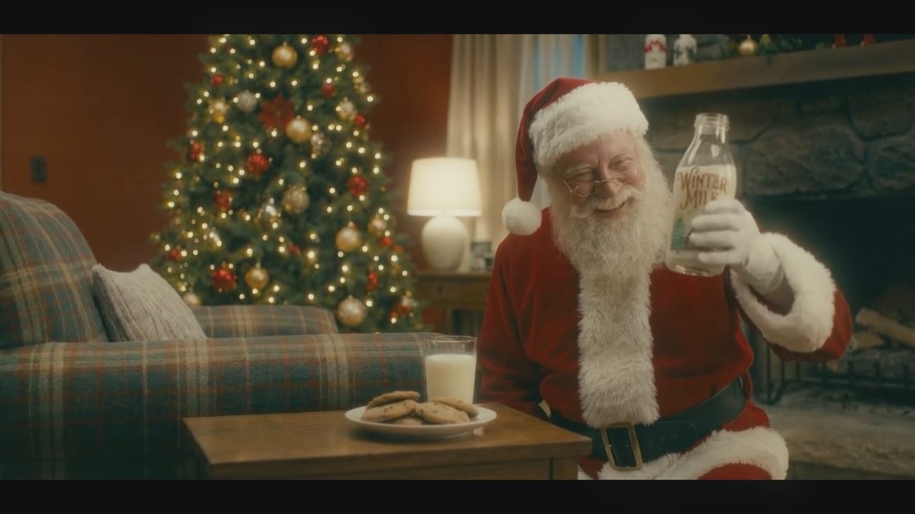 Weihnachtsmann mit der Winter-Milk-Flasche vor dem Weihnachtsbaum